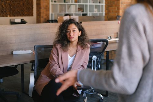 A manager leaning in and listening carefully during a one-on-one conversation, the first step in managing psychosocial hazards at work