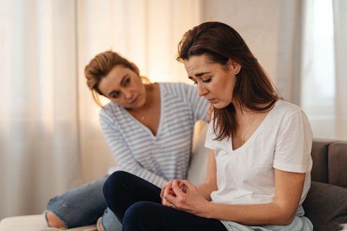 A woman gently comforting a friend on a couch, the kind of support that helps with healing fear of abandonment