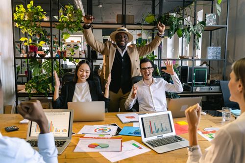 A relaxed team laughing together around a meeting room table, showing the result of managing job demands at work well