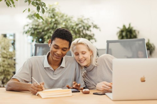 Two colleagues laughing together over their work at a shared desk, with job demands under control
