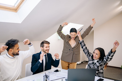 Colleagues laughing together around a table in a bright modern office, showing how trust issues in relationships also shape working life