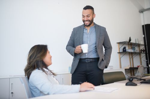 Colleagues in their forties talking easily in a bright modern office, showing nervous system regulation supported at work