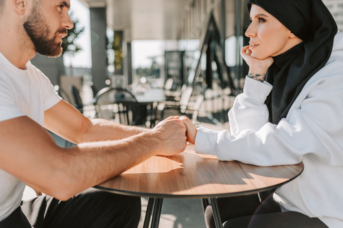 A couple sitting close and holding hands as they talk in daylight, the beginning of healing trust issues in relationships