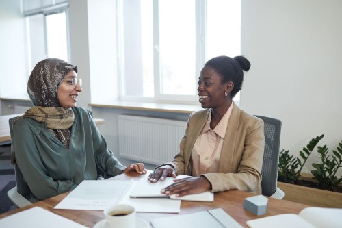 Two colleagues smiling through a supportive check-in at a desk