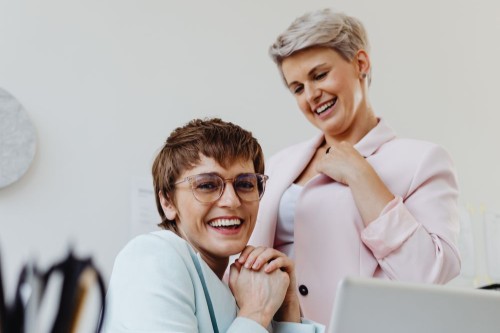 A colleague sharing a laugh with a smiling woman at her desk, a reminder that no one should feel invisible at work