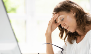 Chronic stress symptoms being experienced while a woman is sitting at her computer