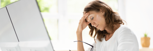 Chronic stress symptoms being experienced while a woman is sitting at her computer