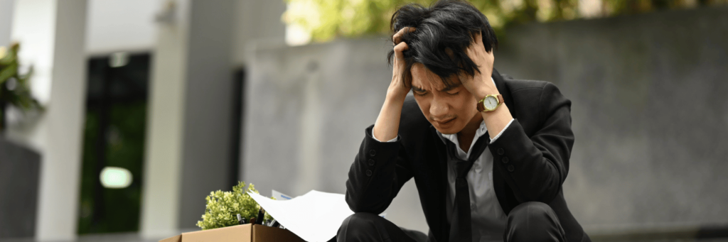 Fear of failure and how a young man is feeling stressed, sitting down, wearing a black suit