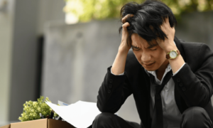 Fear of failure and how a young man is feeling stressed, sitting down, wearing a black suit