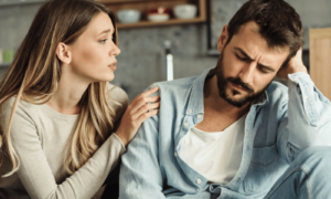 People-pleasing as a woman in a beige top comforts a man in a blue top and tries to do the right thing