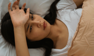 Stress and sleep being affected as a woman lies awake at night overthinking