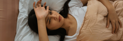 Stress and sleep being affected as a woman lies awake at night overthinking