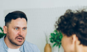 A couple in their forties laughing together in a bright kitchen, showing ease and trust rather than jealousy in relationships
