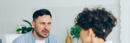 A couple in their forties laughing together in a bright kitchen, showing ease and trust rather than jealousy in relationships