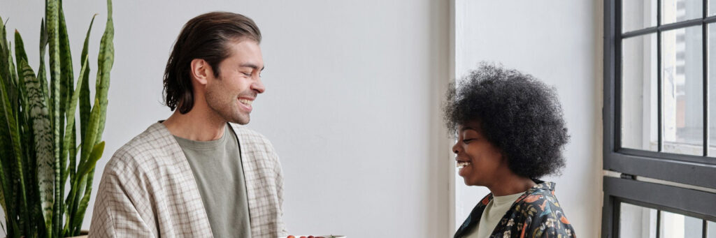 A man and woman in their forties talking and laughing together in a bright kitchen, showing what it looks like when resentment in relationships has eased