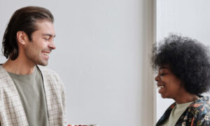 A man and woman in their forties talking and laughing together in a bright kitchen, showing what it looks like when resentment in relationships has eased