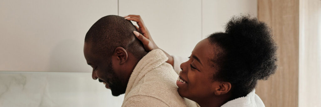 A couple in their forties talking easily over coffee in a bright kitchen after a good night, showing what balanced stress and sleep look like