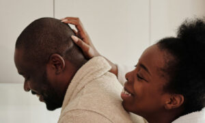 A couple in their forties talking easily over coffee in a bright kitchen after a good night, showing what balanced stress and sleep look like