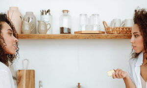Two women in their forties talking easily over coffee in a bright modern kitchen, showing what self-worth and boundaries look like in practice
