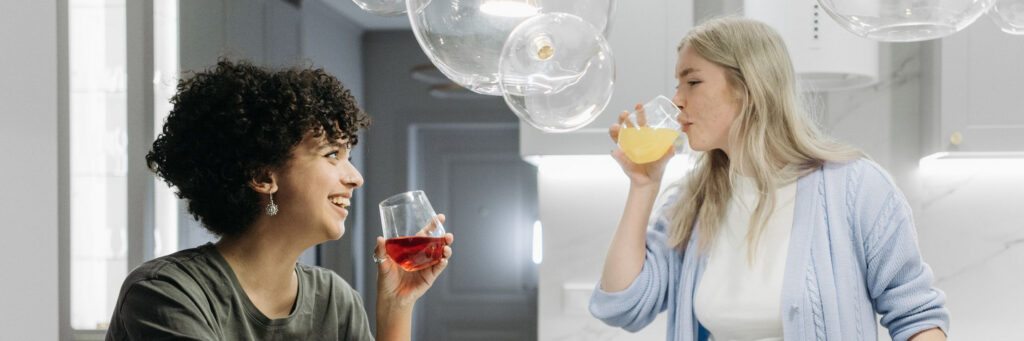 Two women in their forties laughing together in a bright, colourful kitchen, showing the link between colour and mood at home