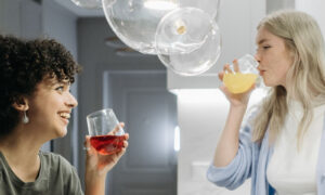 Two women in their forties laughing together in a bright, colourful kitchen, showing the link between colour and mood at home