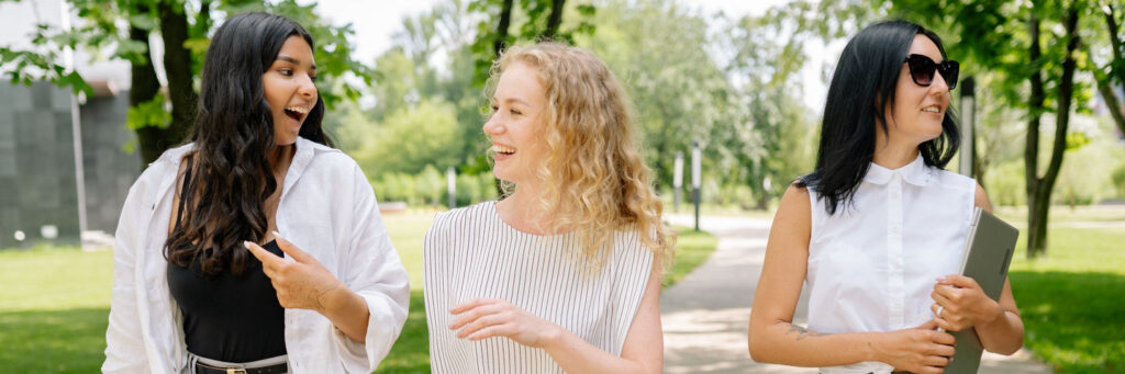 Two adults walking and talking together on a bright tree-lined path, showing the link between movement and energy levels