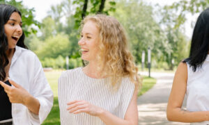 Two adults walking and talking together on a bright tree-lined path, showing the link between movement and energy levels