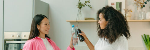 Two women in their forties talking and laughing in a bright modern kitchen, showing what life looks like on the other side of emotional numbness