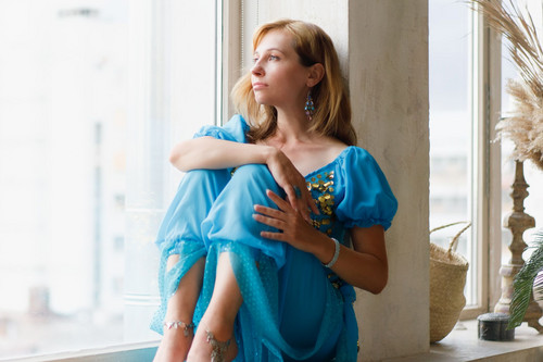 A woman in her forties standing at a bright window looking thoughtful, showing what feeling stuck in life can look like
