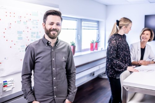 Colleagues at ease in a bright, modern office, talking easily rather than people pleasing