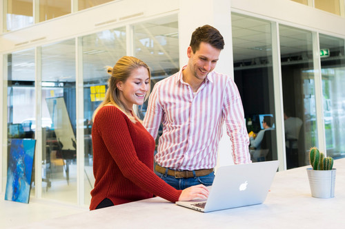Colleagues in their forties talking easily in a bright, modern office, showing colour and mood at work
