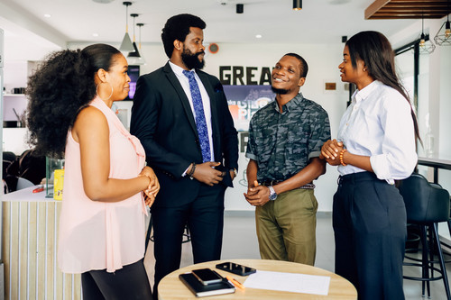 Colleagues in their forties talking easily around a table in a bright modern office, showing a workplace where low energy emotions can be spoken about