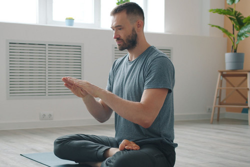 A man in his forties sitting quietly and breathing slowly in a bright modern room, beginning to settle the link between stress and sleep