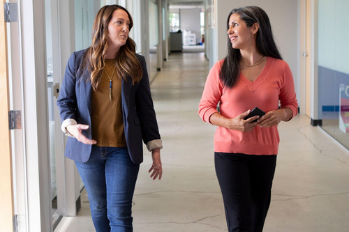 Two colleagues in their forties talking easily in a bright modern office, showing a workplace where resentment in relationships at work is addressed early