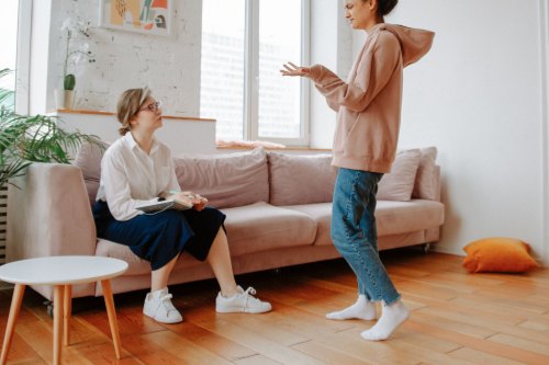 Two women in their forties talking honestly in a bright, modern room, the first steps away from people pleasing