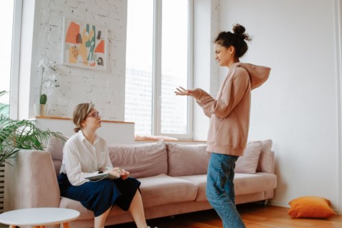 Two women in their forties talking honestly in a bright, modern room, the first steps away from people pleasing
