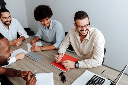 Colleagues standing and talking easily in a bright modern office, showing movement and energy levels during the working day