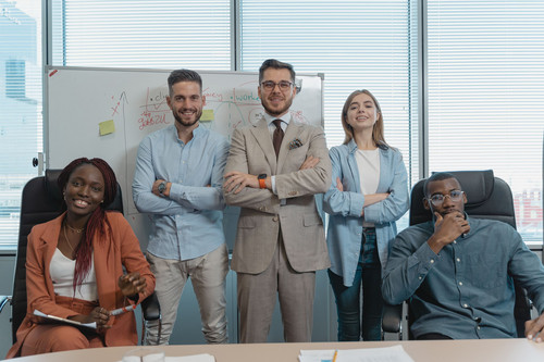 A relaxed team of professionals laughing together in a bright modern meeting room, a workplace where imposter syndrome loses its grip
