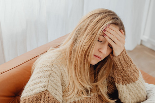 A woman sitting still on a sofa in a bright room looking flat and tired, the kind of day when movement and energy levels have dropped