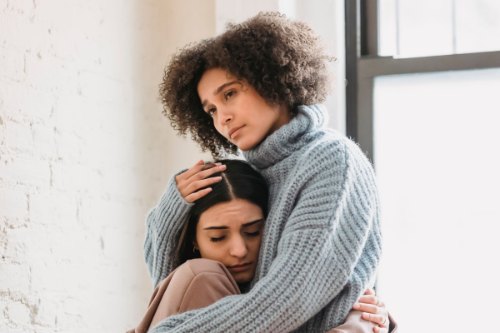 A friend holding a worried woman close, the kind of reassurance that eases fear of abandonment