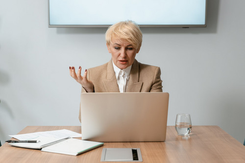 A manager on a video call with a remote colleague in a bright modern office, beginning to address remote work psychosocial risks