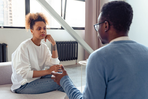 A woman and man talking honestly on a sofa in daylight, showing the first conversation that begins to shift resentment in relationships