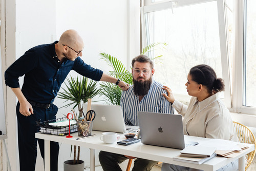 A manager listening carefully to a colleague across a desk in a sunlit office, the conversation at the centre of how to review workload at work