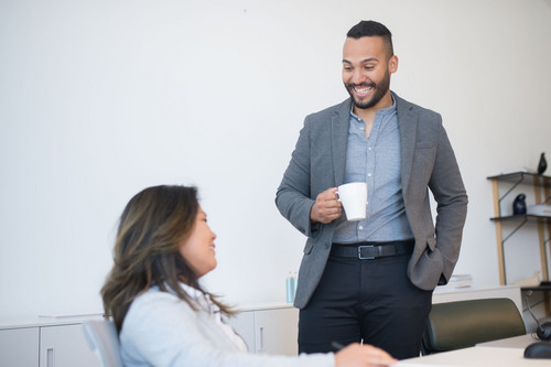 Colleagues talking easily around a meeting table in a bright modern office, a team at ease after a manager learned how to review workload at work