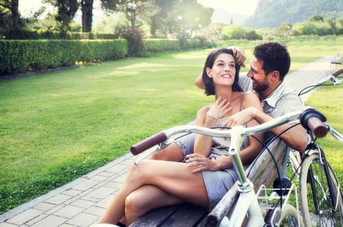happy couple cuddling on park bench