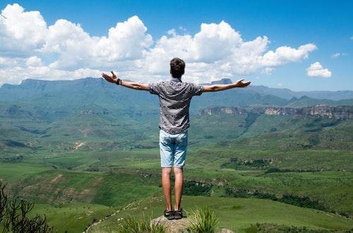 Man standing on a rock with his arms spread