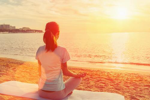 a woman meditating under the sun