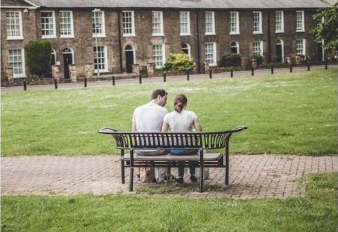 Father sitting with his daughter talking on a park bench.