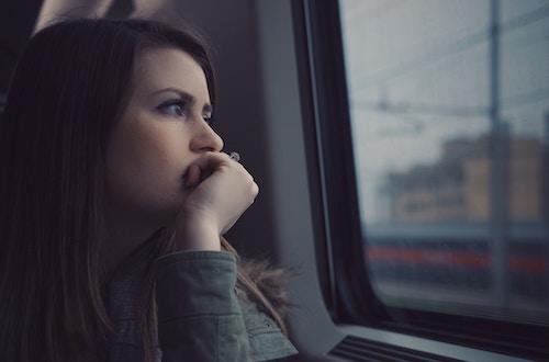 Woman looking out a train window contemplatively