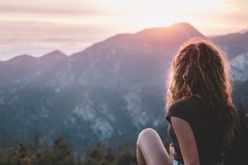 Girl watching sunset over mountain